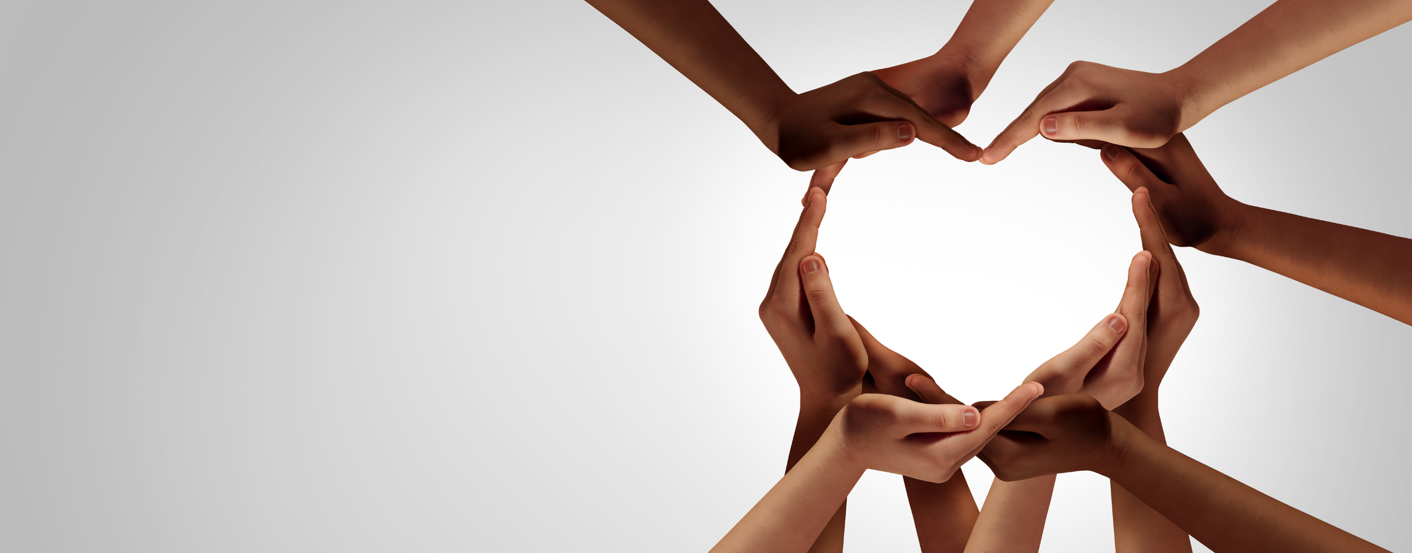 A close up of individuals' hands creating a heart shape.
